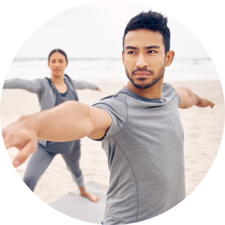 Man and Woman performing yoga on sea shore 