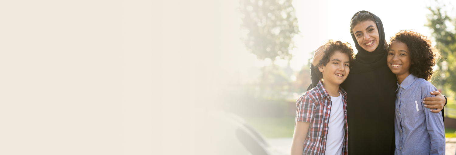 A mother in black burqa standing with her two kids, all three smiling joyfully
