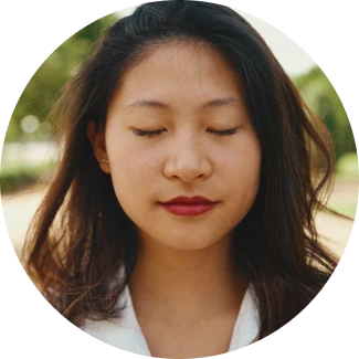 A smiling female with closed eyes meditating