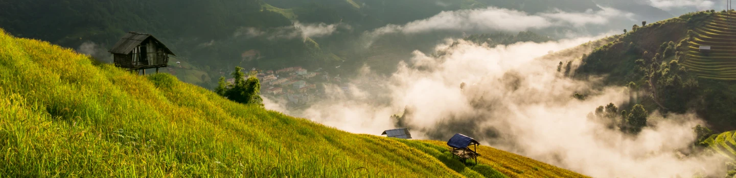 Serene view of mist-covered hills with wooden cabins and terraced fields
