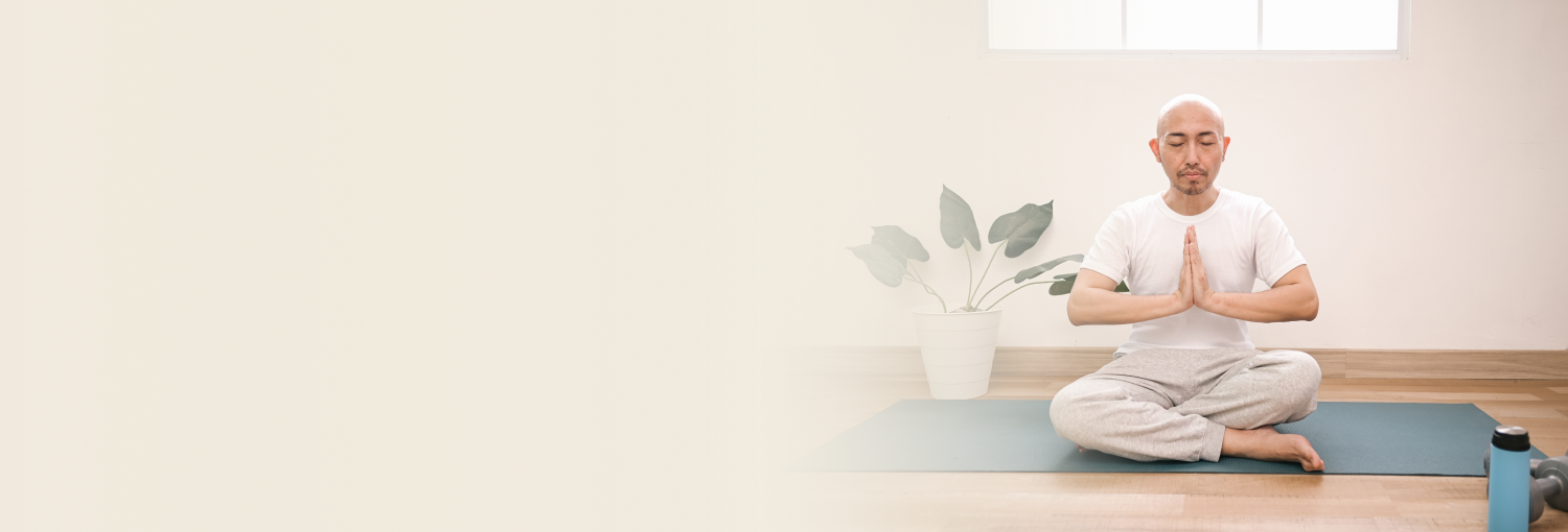 A young woman meditating with eyes closed and hands in prayer position on a sunny beach, embodying mindfulness and calm