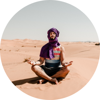 A man wearing Keffiyeh meditating in middle of a dessert