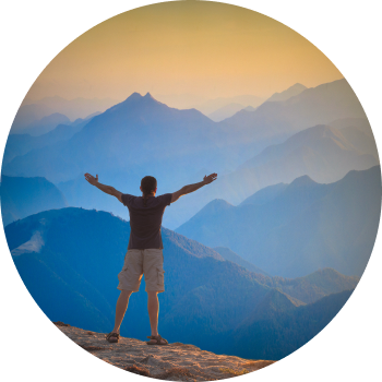 A man with opened arms standing at top of mountain representing the courage to overcome limitations and discover his full potential.