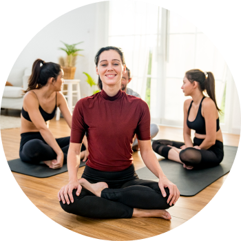A group of woman sitting cross-legged in a yoga studio, chatting with each other after a yoga session