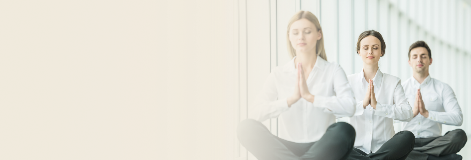 Group of professionals in white attire practicing meditation in office setting